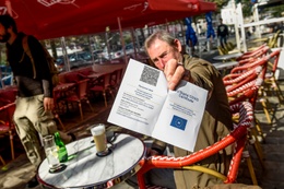 Een man op een Brussels terras toont zijn Covid Safe Ticket (CST) 