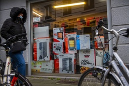 20220117 Een man met mondmasker loopt langs een uitstalraam van een winkel met huishoudgerief petroleumkachel verwarmingstoestel