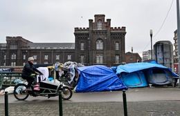 Januari 2023: asielzoekers in een geïmproviseerd tentenkamp aan de brug over het kanaal bij het Klein Kasteeltje, de verbiding tussen de Koolmijnenkaai en de Negende Linielaan aan de Kleine Ring. Een man op een cargobike fietst erlangs