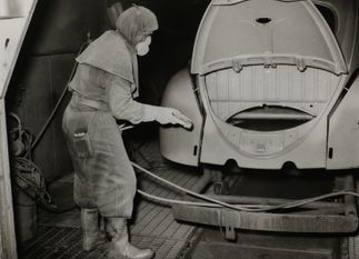 Een arbeider aan het werk in de spuitafdeling van Volkswagen Vorst in 1961